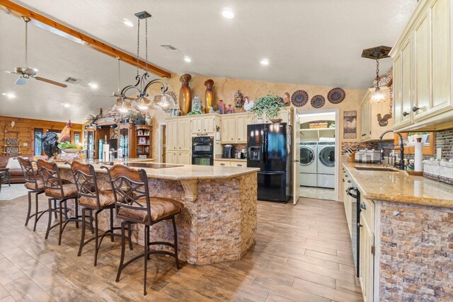 kitchen with high vaulted ceiling, washing machine and clothes dryer, a sink, black appliances, and ceiling fan