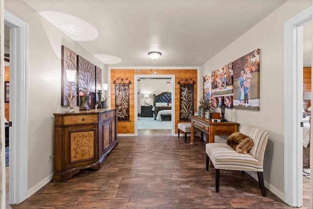hallway featuring wood walls, baseboards, and dark wood-style floors