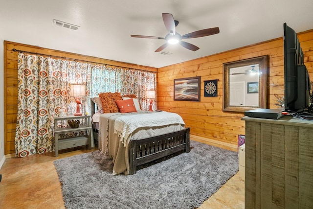 bedroom with baseboards, wooden walls, visible vents, and a ceiling fan