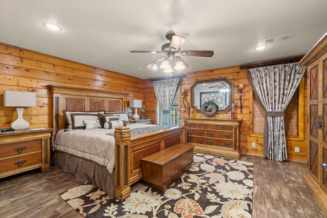 bedroom featuring dark wood finished floors, wooden walls, visible vents, and recessed lighting