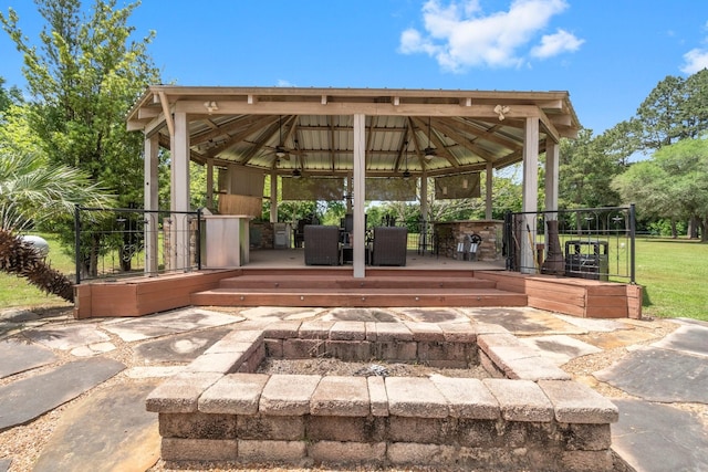 view of community with a gazebo, a yard, a wooden deck, and an outdoor fire pit