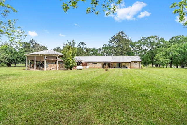 rear view of property with a gazebo, a yard, and metal roof