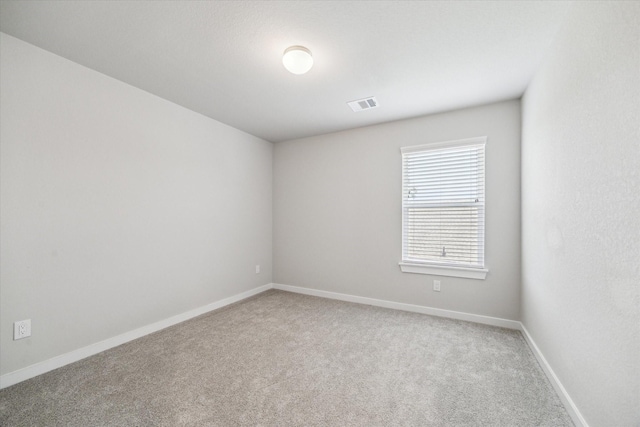 empty room with baseboards, visible vents, and carpet