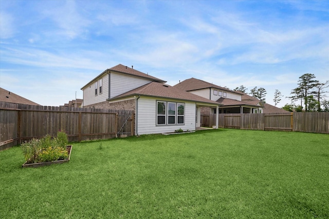 rear view of property featuring a fenced backyard, a vegetable garden, a yard, and roof with shingles