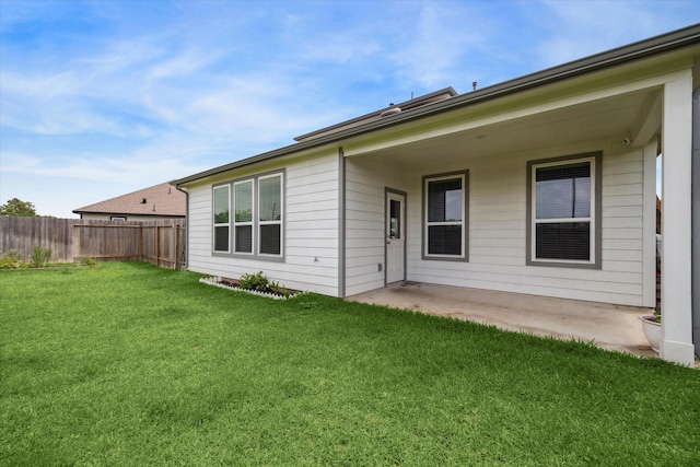 rear view of house with a patio, fence, and a yard