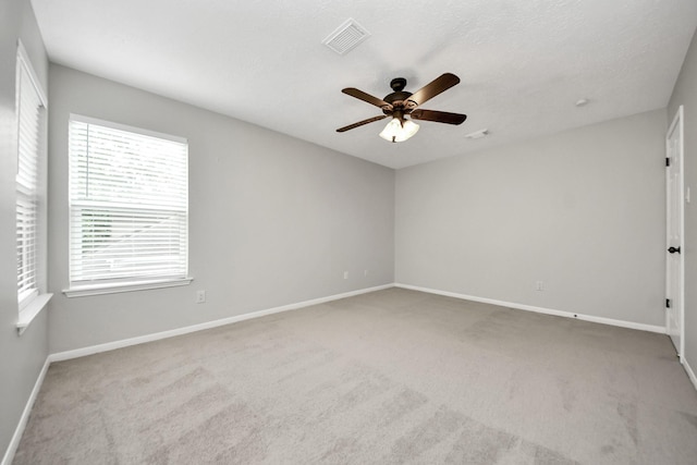 carpeted empty room with baseboards, ceiling fan, and visible vents