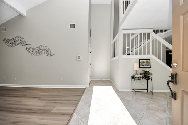 entryway with visible vents, stairs, beam ceiling, and high vaulted ceiling