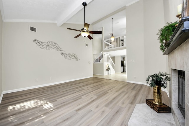 unfurnished living room with ceiling fan, light wood-style floors, a glass covered fireplace, visible vents, and stairway
