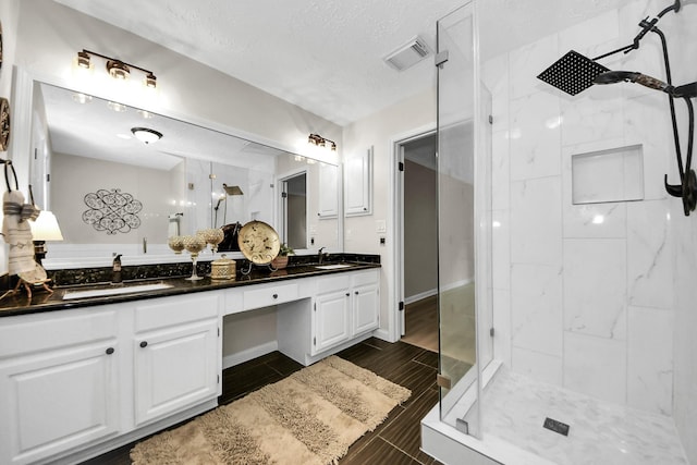 bathroom with a sink, a shower stall, double vanity, and visible vents