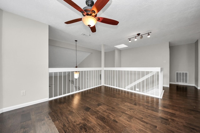 empty room featuring visible vents, a ceiling fan, baseboards, and wood finished floors