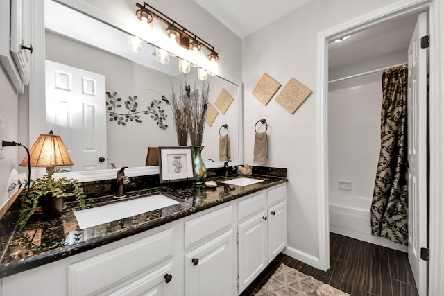 full bathroom with double vanity, baseboards, a sink, and shower / bath combo