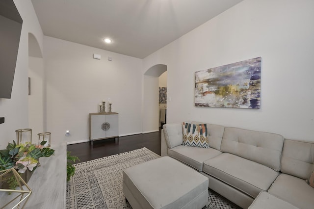 living room featuring baseboards, wood finished floors, arched walkways, and recessed lighting