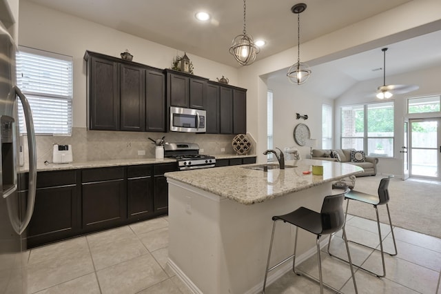 kitchen with a kitchen breakfast bar, stainless steel appliances, a sink, decorative backsplash, and open floor plan