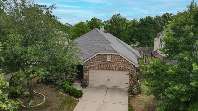 view of front facade with driveway, a chimney, a shingled roof, fence, and brick siding
