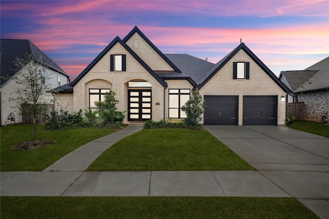 french country inspired facade with fence, driveway, a front lawn, and brick siding