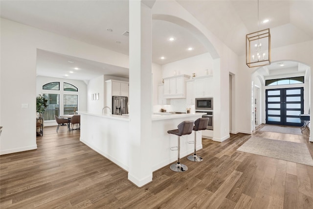 entryway with baseboards, arched walkways, wood finished floors, and recessed lighting