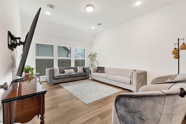 living room featuring light wood finished floors, visible vents, and lofted ceiling