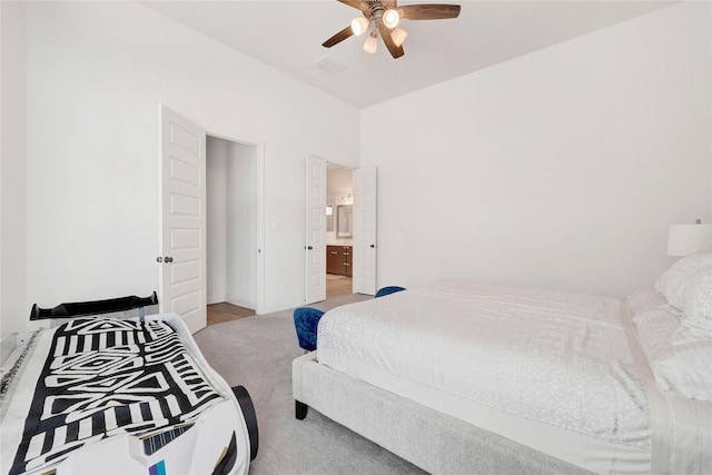 bedroom with connected bathroom, ceiling fan, and light carpet