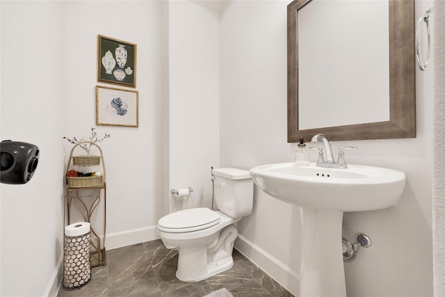 bathroom featuring marble finish floor, baseboards, and toilet