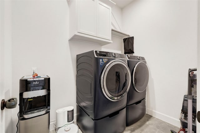 washroom featuring cabinet space, baseboards, and washer and dryer