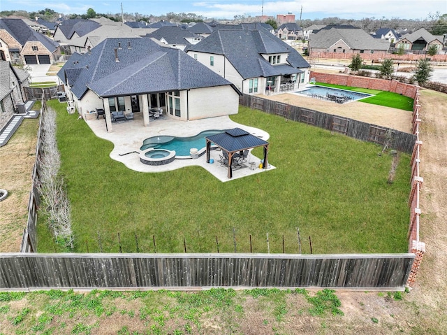 exterior space with a fenced backyard, a pool with connected hot tub, a residential view, and a patio