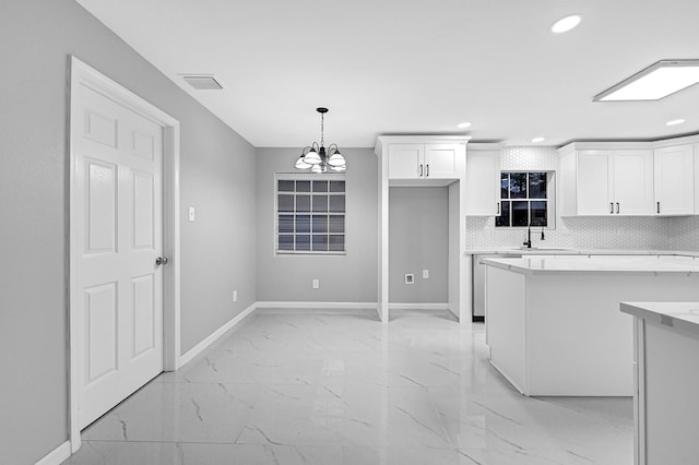kitchen with marble finish floor, light countertops, white cabinets, baseboards, and recessed lighting