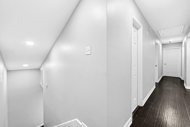 hall featuring attic access, baseboards, and dark wood-style floors