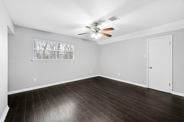 spare room featuring visible vents, a ceiling fan, baseboards, and dark wood-style floors