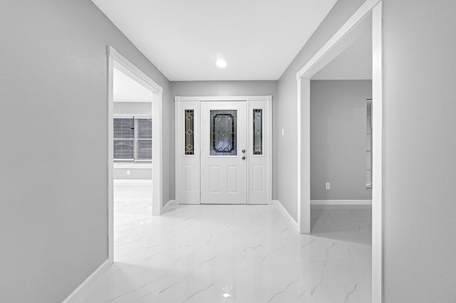 entrance foyer featuring marble finish floor and baseboards