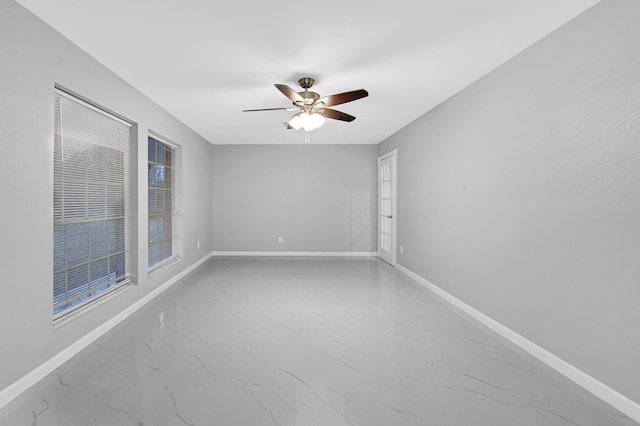 spare room featuring marble finish floor, baseboards, and ceiling fan