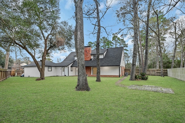 back of house with a yard, a chimney, a fenced backyard, and a shingled roof