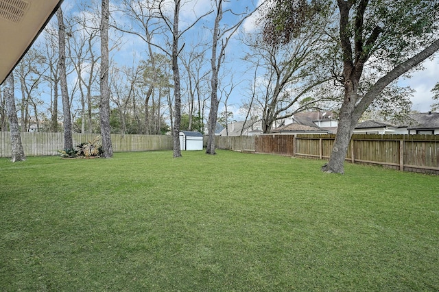 view of yard featuring a fenced backyard, a storage unit, and an outdoor structure