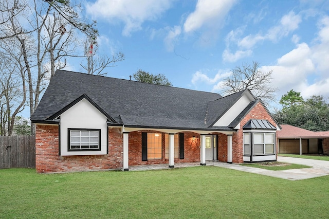 view of front facade featuring a shingled roof, covered porch, fence, a front yard, and brick siding