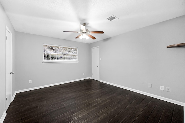spare room with baseboards, visible vents, dark wood-style floors, and ceiling fan
