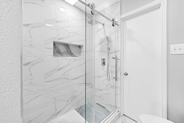 full bathroom with a textured wall, a marble finish shower, and toilet