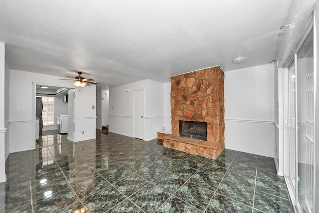7954 Grove Ridge Dr, Houston, TX 77061 - unfurnished living room featuring ceiling fan, baseboards, a stone fireplace, and a textured ceiling