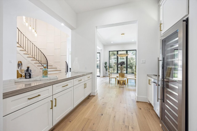 4016 Branard St, Houston, TX 77027 - bar featuring decorative light fixtures, baseboards, light wood-style floors, and stairway