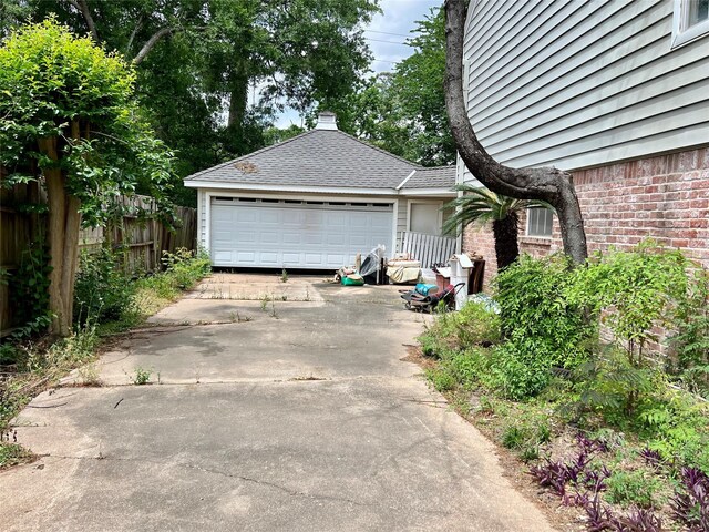 garage featuring driveway and fence