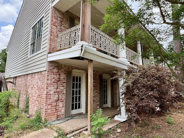 view of side of property featuring a balcony and brick siding