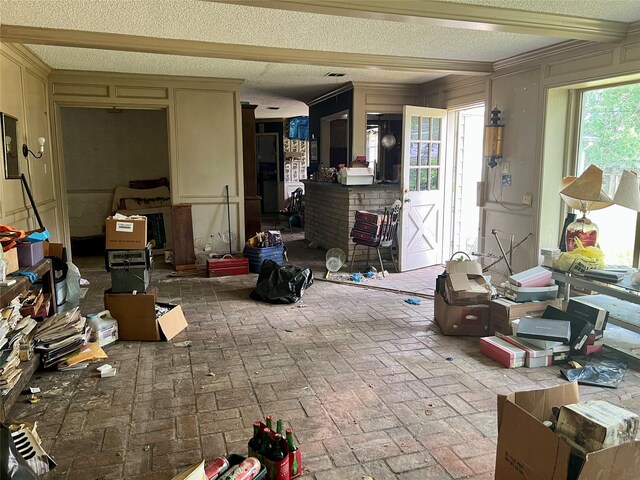 living room with brick floor, beam ceiling, and a textured ceiling