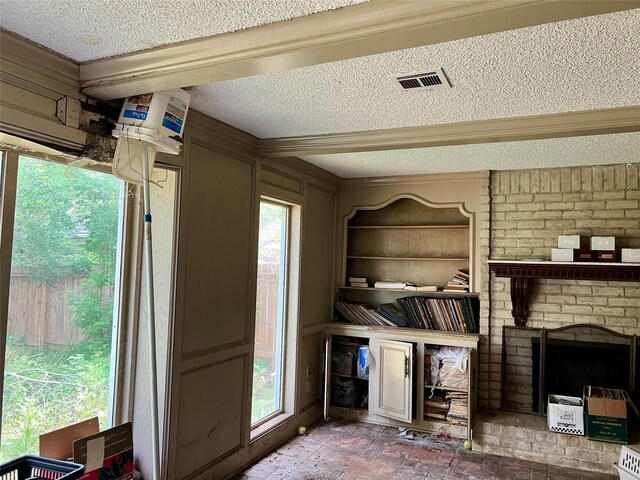 interior space with a fireplace, a textured ceiling, crown molding, and visible vents
