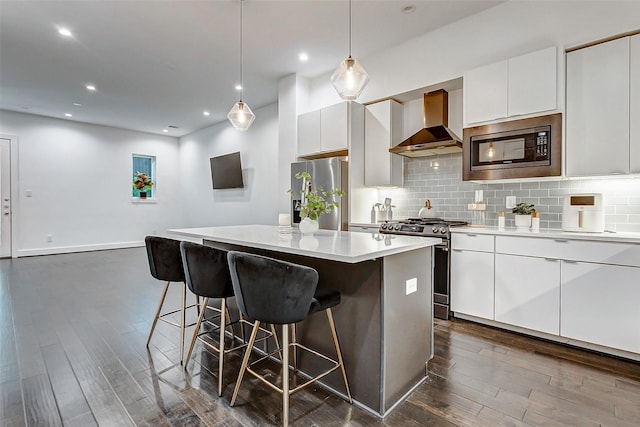 5841 Dolores St, Houston, TX 77057 - kitchen with wall chimney exhaust hood, stainless steel appliances, dark wood finished floors, a kitchen breakfast bar, and a kitchen island