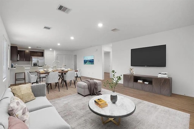 living room with light wood-style floors, visible vents, and recessed lighting