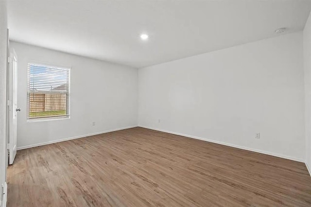 unfurnished room with baseboards, wood finished floors, and recessed lighting