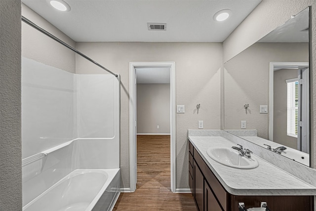 full bathroom with visible vents, baseboards, wood finished floors, vanity, and tub / shower combination