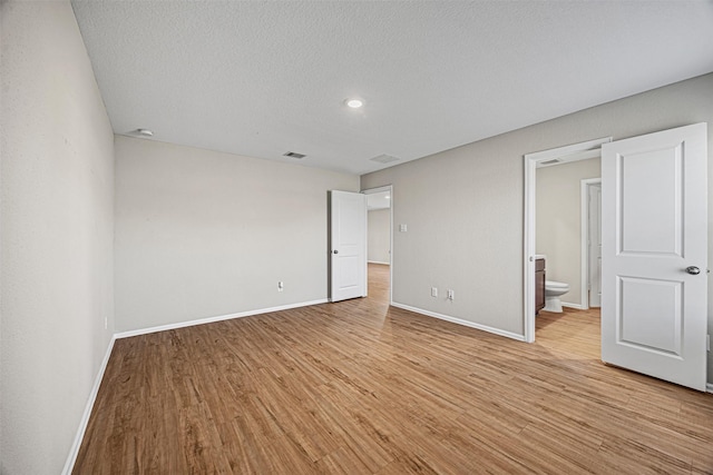 unfurnished bedroom featuring light wood finished floors, baseboards, a textured ceiling, and visible vents