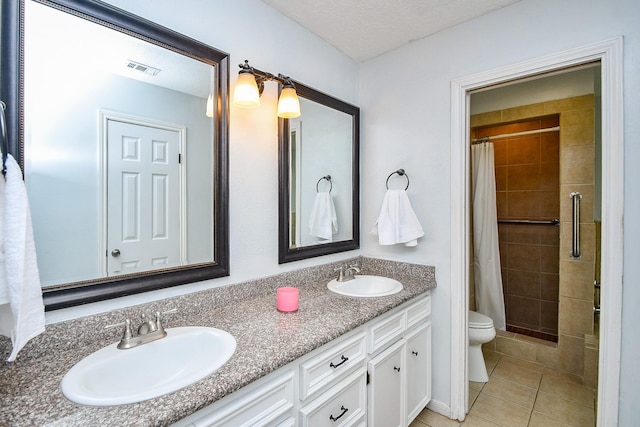 full bathroom featuring a sink, tile patterned floors, a tile shower, and double vanity