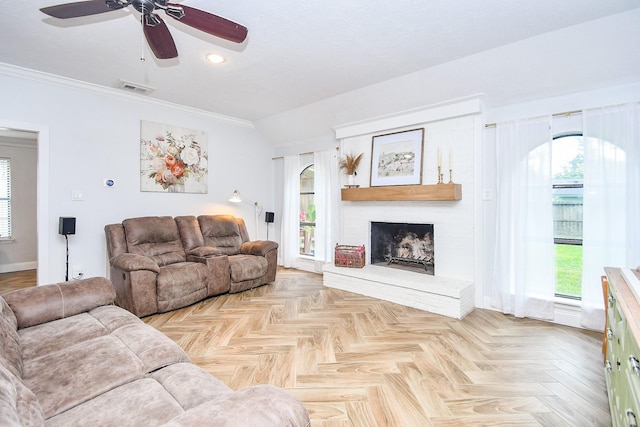 living area featuring a ceiling fan, visible vents, crown molding, a fireplace, and baseboards