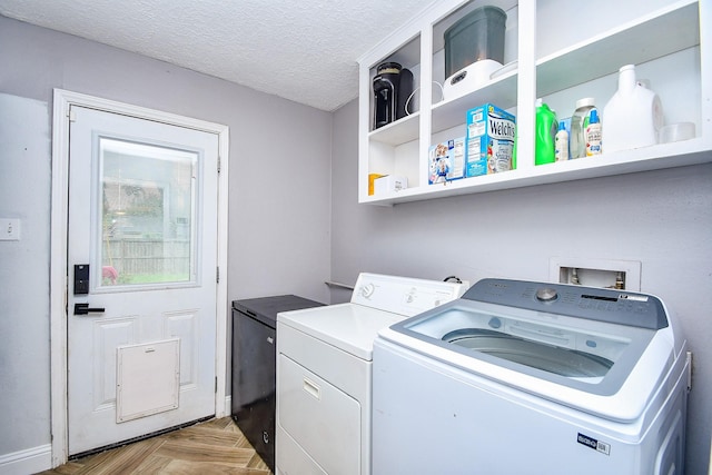 laundry room with laundry area, baseboards, a textured ceiling, and washing machine and dryer