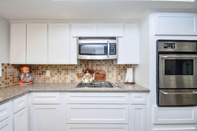 kitchen with white cabinets, a warming drawer, tasteful backsplash, and stainless steel appliances